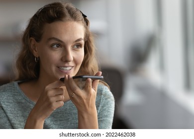 Happy gen Z girl recording audio message on smartphone. Millennial making phone call on speaker, giving command to virtual assistant, using voice recognition app, chatting on smartphone messenger - Powered by Shutterstock