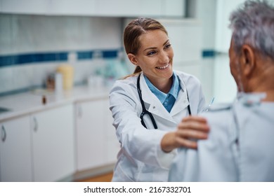 Happy General Practitioner And Her Senior Patient Talking During Medical Exam At Doctor's Office.