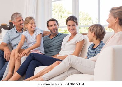 Happy generation family sitting on couch at home and talking. Portrait of extended family group sitting together in a conversation. Smiling mother and father with children and grandparent.
