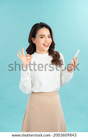 Happy gesturing young cheerful smiling business woman with phone or support operator, showing okay gesture, 
