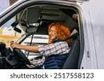 Happy ginger woman truck driver driving a truck.People and industrial transportation concept.