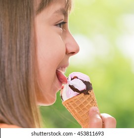 Happy Girl 10-11 Year Old Eating Ice Cream Cone. Outdoor Portrait.