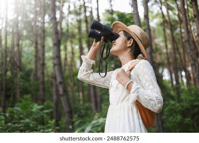 Happy girl with backpack looking through binoculars in the outdoors. adventure or bird watching and search in forest - Powered by Shutterstock