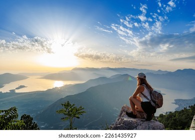 Happy girl with a backpack is on the edge of a high mountain in Montenegro - Powered by Shutterstock