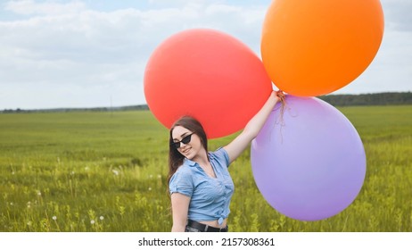Happy girl with big multicolored balloons posing on the field. - Shutterstock ID 2157308361