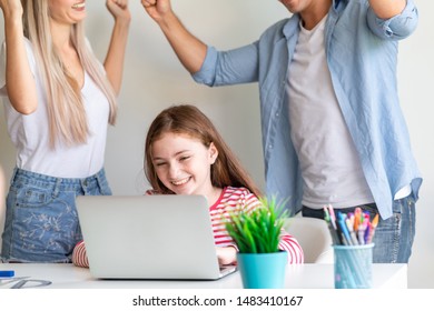 Happy Girl With Big Smile After See Her Exam Result From Laptop With Dancing Parent In Background. Online Education Concept.