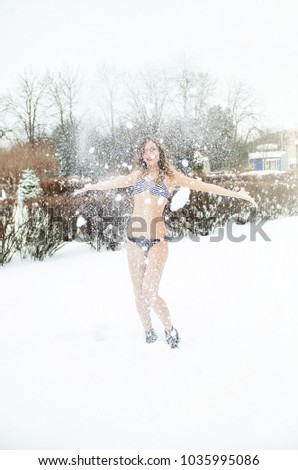 Happy girl in bikini playing with snow in city center