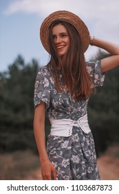 Happy Girl In Blue Dress In Flower And Corset. Woman In Straw Hat With Brunette With Straight Hair. Portrait Of Smiling Girl In Park Or Forest.