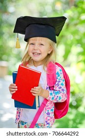 Happy girl with books  in graduation cap 
