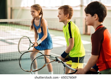 Happy girl and boys playing tennis