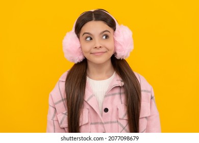 Happy Girl Child In Warm Winter Fur Earmuffs Smile With Sly Look Yellow Background, Intrigue