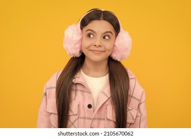 Happy Girl Child In Warm Winter Fur Earmuffs Smile With Sly Look Yellow Background, Intrigue