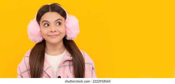 Happy Girl Child In Warm Winter Fur Earmuffs Smile With Sly Look Yellow Background, Intrigue. Child Face, Horizontal Poster, Teenager Girl Isolated Portrait, Banner With Copy Space.