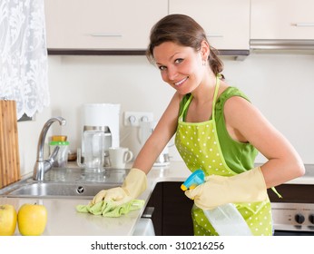 Happy Girl Cleaning Furniture In Kitchen At Home
