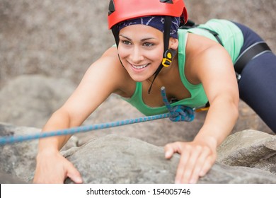 Happy girl climbing rock face wearing red helmet - Powered by Shutterstock