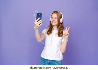 Happy girl communicates via video communication using a mobile phone on a colored background in the studio, Caucasian girl rejoices in communication - Powered by Shutterstock