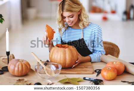 happy girl is cutting a pumpkin and is preparing for the holiday Halloween
