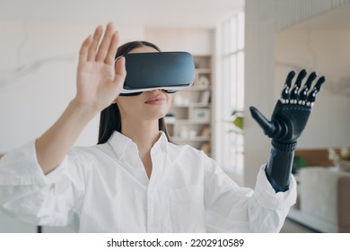 Happy Girl With A Disability In Vr Glasses At Home. Young European Woman With Artificial Hand Is Excited With 3d Cyber Vision. Amputee Has Modern Bionic Limb.