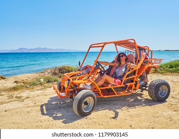 A happy girl driving a Buggy on a dune of beach with the Aegean sea in background. Greek island of Kos. South Aegean region, Greece.