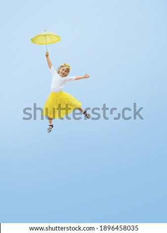 
Happy girl flies on an umbrella against the blue sky.