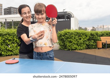 Happy girl friends playing ping pong table tennis, having fun together - Powered by Shutterstock