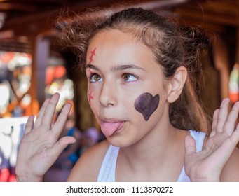 Happy Girl With Funny Expression. Heart And Scar Are Painted On The Face