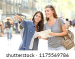 Happy girl helping to a tourist who asks direction in the street