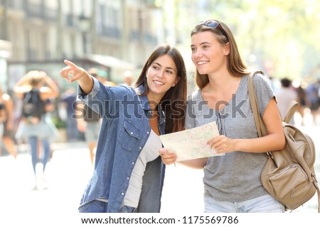 Happy girl helping to a tourist who asks direction in the street