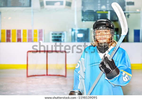 Happy girl in\
hockey uniform posing with\
stick