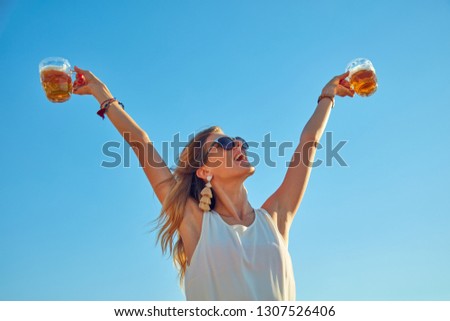 Happy girl holding beer glass outdoors.