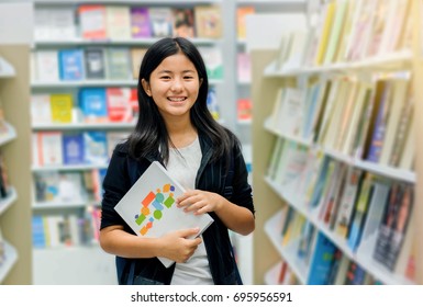 Happy Girl Holding Book In Library,Asian Teenager Student In Book Store