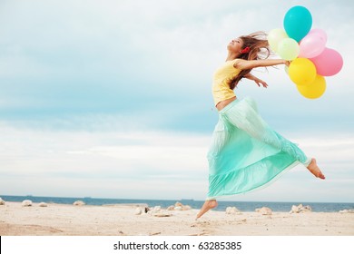 Happy girl holding bunch of colorful air balloons at the beach - Powered by Shutterstock