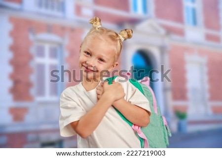 A happy girl holds a school backpack on her shoulders, back to school, school days, the child goes to classes, close-up, portrait of a girl.