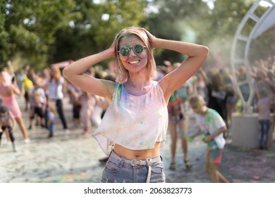 Happy girl at the Holi Fest festival of colors in the city park hanging out to the music in the summer on vacation. A traditional urban holiday of dry paints. Young woman with paints on her face. - Powered by Shutterstock