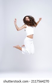 Happy girl jumping for joy, mid-air pose, sporty, active and energetic, white background
