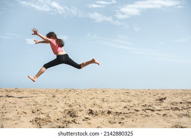 Happy girl jumping in the sand on the beach