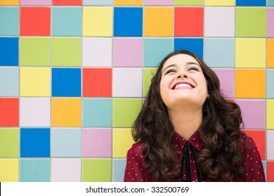 Happy girl laughing against a colorful tiles background. Concept of joy - Shutterstock ID 332500769