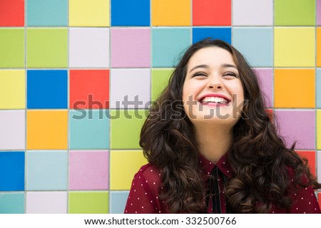 Happy girl laughing against a colorful tiles background. Concept of joy