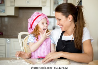 Happy Girl Licking Fingers And Looking At Mother