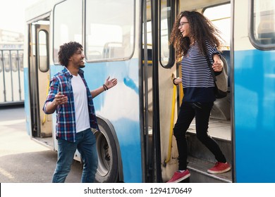 Happy girl with long curly hair getting out the bus while her boyfriend waiting for her with open arms. - Shutterstock ID 1294170649
