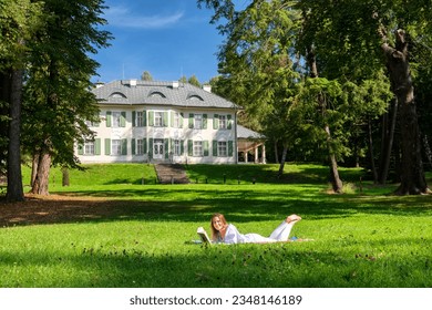 Happy girl lying on a blanket in park in front of manor house in Oscadnica, Slovakia
