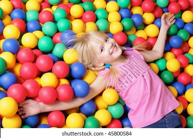 Happy girl lying on colorful balls and looking at camera - Shutterstock ID 45800584