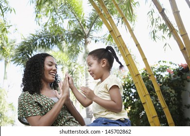 Happy Girl And Mother Playing Patty Cake In Park