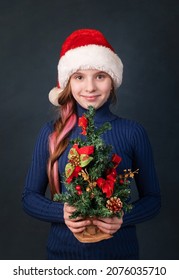 Happy Girl In A New Year Cap For Christmas With A Tree In Her Ha