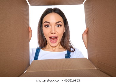 Happy Girl Opening Postal Package. Excited Young Woman Holding Cardboard Box And Looking Inside. Gift, Present, Delivery, Shipment, Sale Concept.