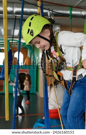 Happy girl passes the cableway, active recreation in the playroom, cableway for the physical development of the child.