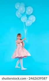 happy girl in pink dress with blue balloons running on blue background: stockfoto
