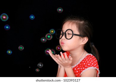 Happy girl play with soap bubbles isolated black background