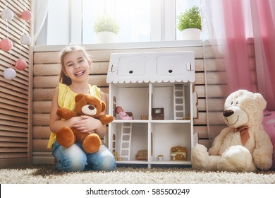 Happy Girl Plays With Doll House And Teddy Bear At Home. Funny Lovely Child Is Having Fun In Kids Room.