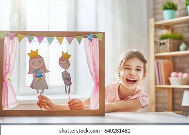 Happy Girl Plays With Performance In The Puppet Theater With Prince And Princess At Home. Funny Lovely Child Is Having Fun In Kids Room.